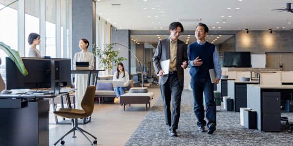 Two colleagues walking and talking in a modern office.