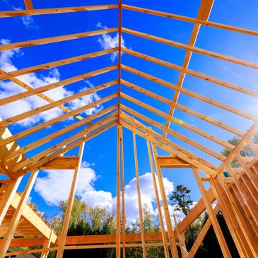 Wooden house framework against a blue sky.