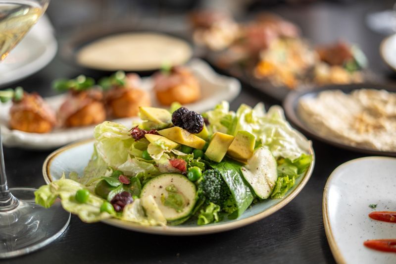 Fresh green salad with avocado, broccoli, peas, and berries, ready for a healthy meal