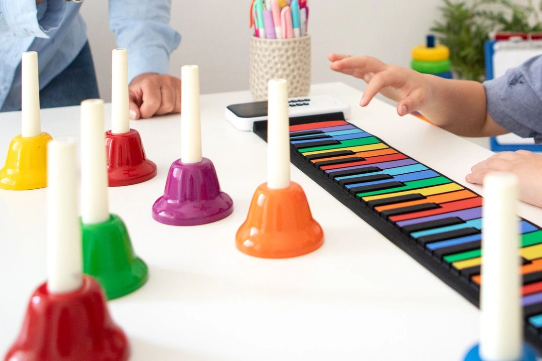 Child playing colorful musical instruments on a table.
