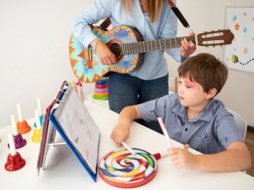 Boy playing colorful musical instrument with woman playing guitar.