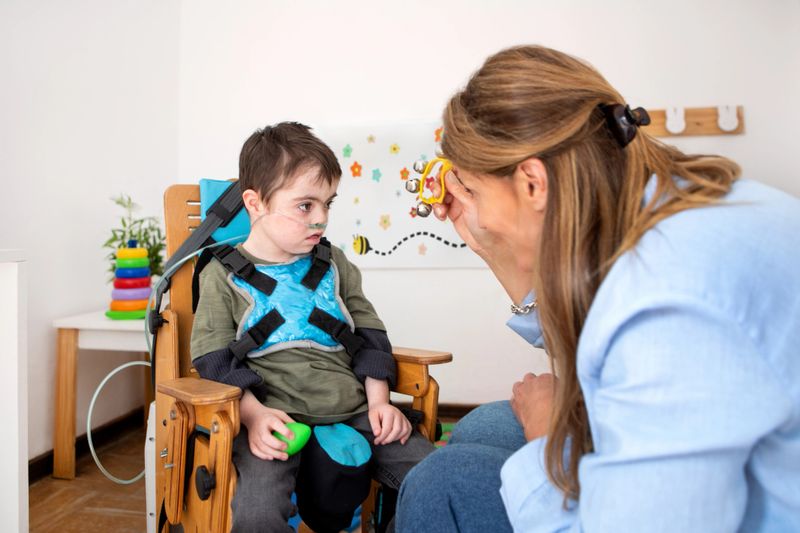 A 6-year-old boy with Down syndrome, West syndrome, and respiratory problems being stimulated with different musical instruments in a session with a female music therapist. West syndrome is a medical condition of epilepsy that affects babies in their first year of life, especially between 3 and 7 months. It is characterized by the triad of infantile spasms, an abnormal brain wave pattern (hypsarrhythmia), and impaired psychomotor development. Early treatment is crucial to try to control seizures and mitigate subsequent neurological deterioration. - Buenos Aires, Argentina