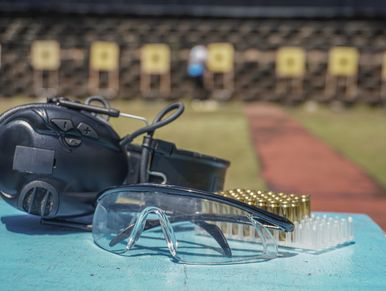 Safety glasses, ear protection, and ammunition on a table at a shooting range.