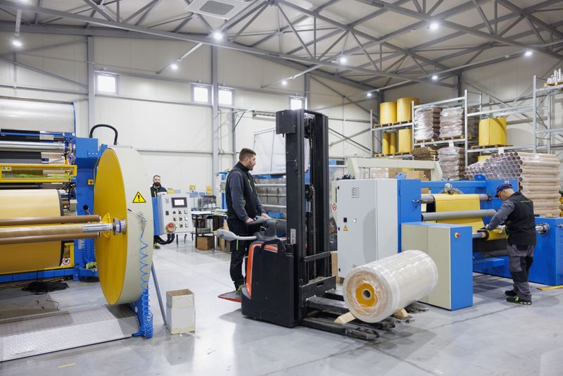 Men working in small-scale industry, production and distribution, using forklift for moving bales of material on pallets