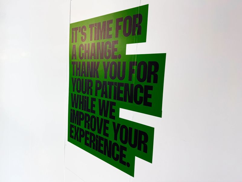 Bold green poster with large black text thanking customers for patience during improvements to their experience.