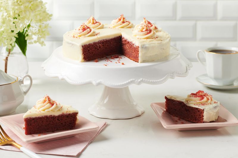 Ruby red cake on a white pedestal with slices removed