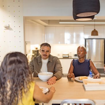 Three people sitting at a kitchen counter having a meal together.