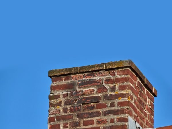 Close-up of a brick chimney against a clear blue sky.