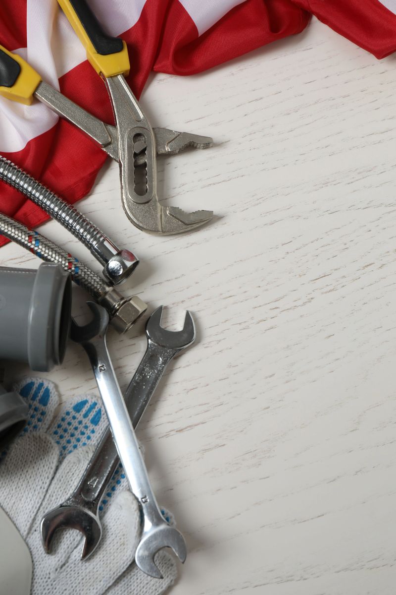 Image of work gloves, tools and American flag on wooden surface symbolizing Labor Day in the USA