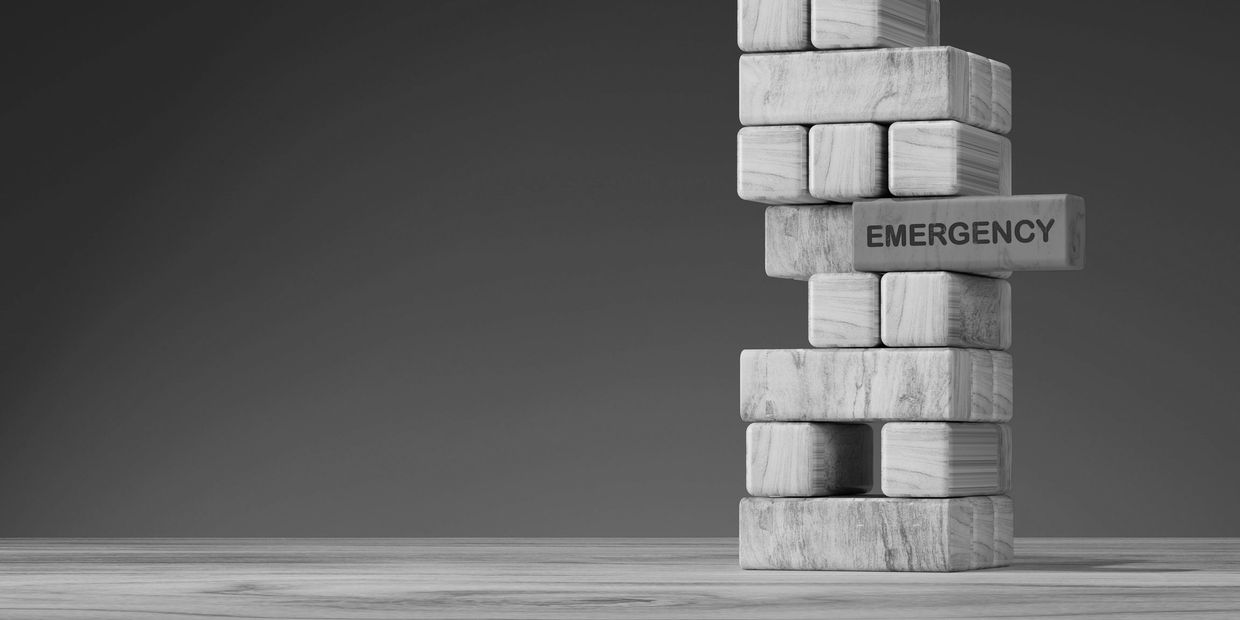 Wooden blocks stacked with a red block labeled 'EMERGENCY' sticking out.