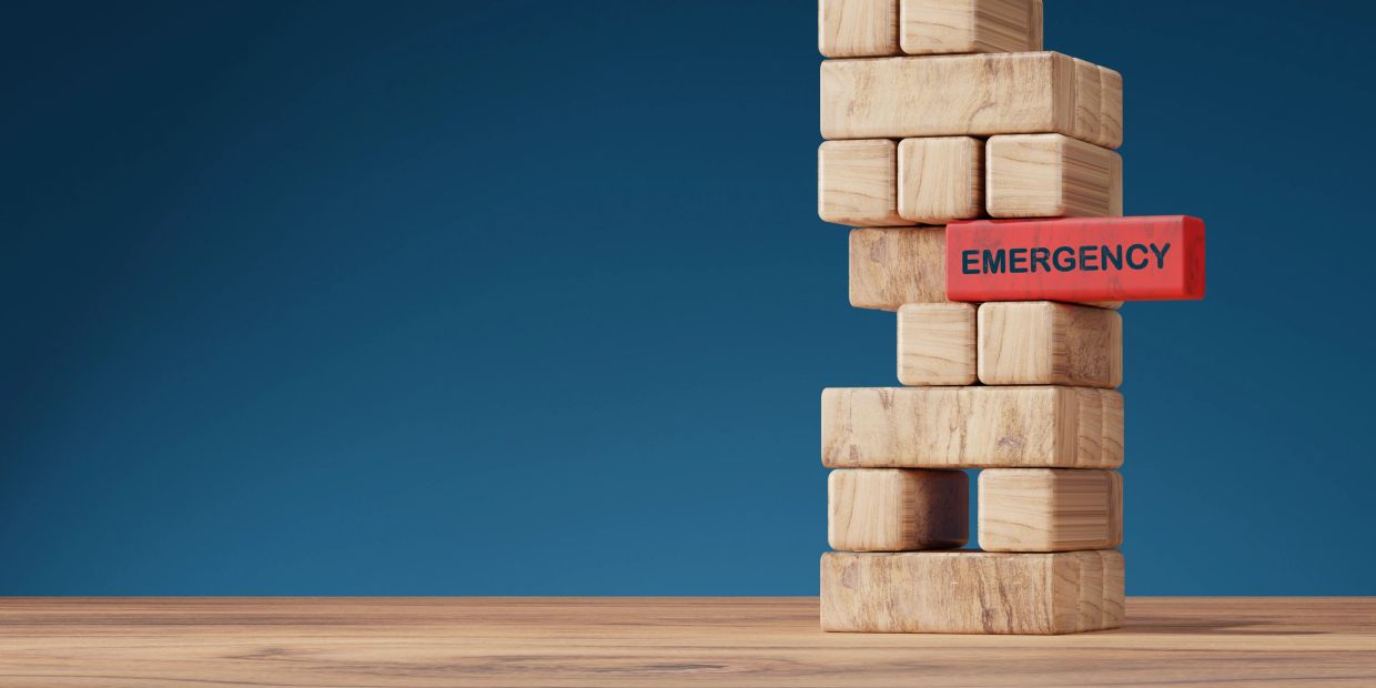 Wooden blocks stacked with a red block labeled 'EMERGENCY' sticking out.