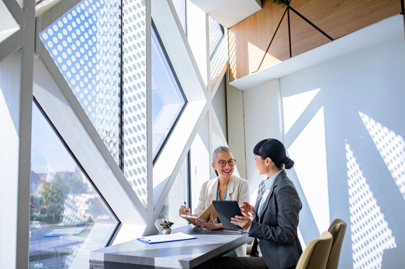Confident businesswomen review data on a digital tablet, symbolizing digital collaboration and modern communication