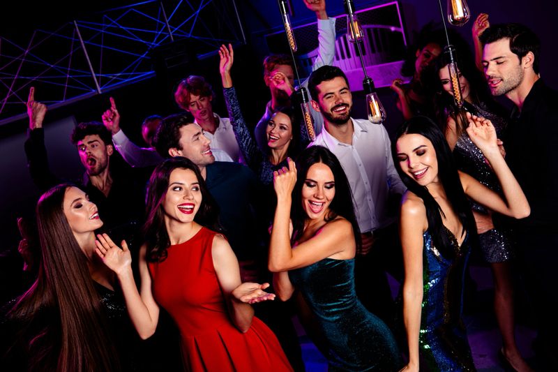 A vibrant group of young adults enjoys a night out at a club party with dancing, bright neon lights, and festive mood. Friends mingle while DJ spins popular tracks for a dynamic celebration.