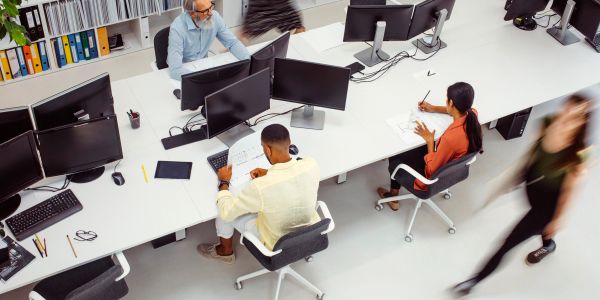 People working on computers in a busy office environment.