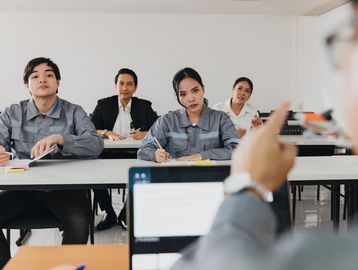 Students attentively listening to a teacher in a classroom.