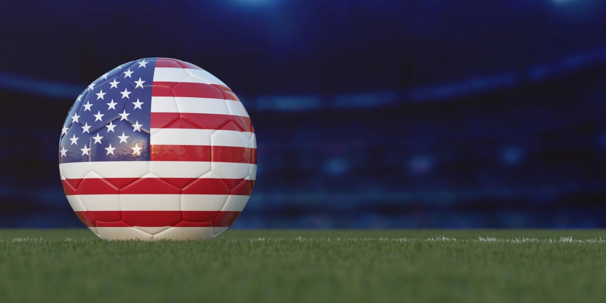 Soccer ball painted with American flag on grass.