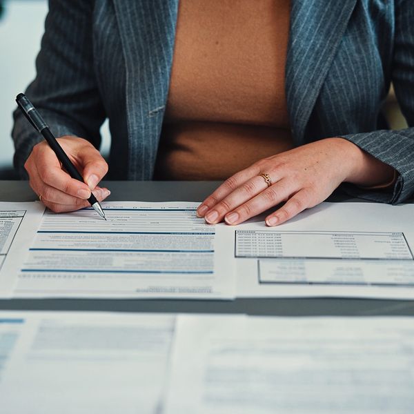 A person writing notes on audit documents at a desk