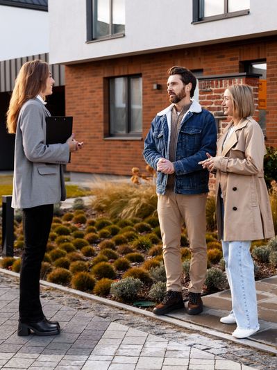 Real estate agent talking to a couple outside a house.