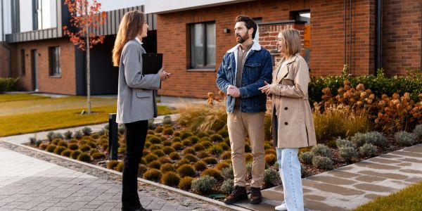 Agente inmobiliaria mostrando una propiedad a una pareja.
