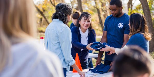 Volunteers distributing shirts at an outdoor event.