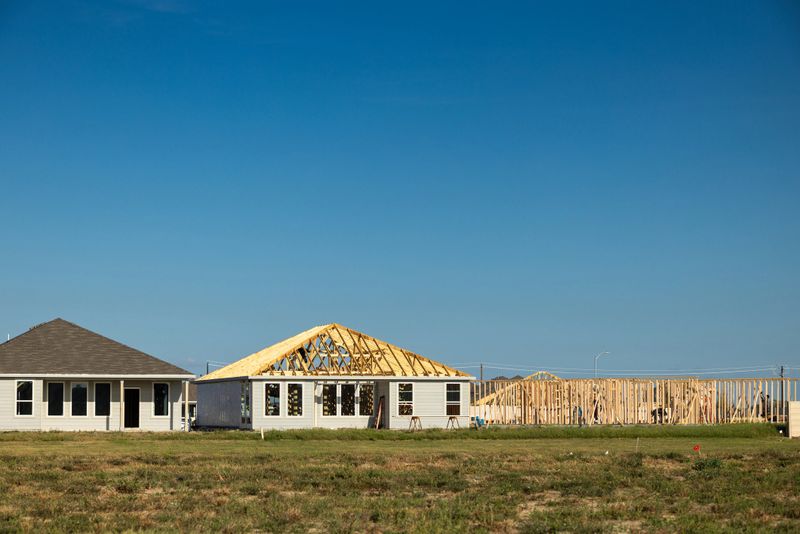 Single-storey houses under construction on a sunny day in Baytown, Texas with copy space in the clear blue sky above.