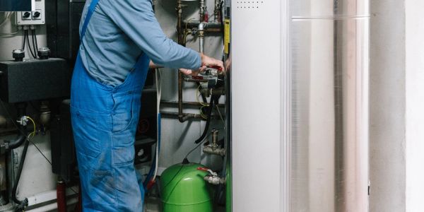 Person repairing heating system in utility room.