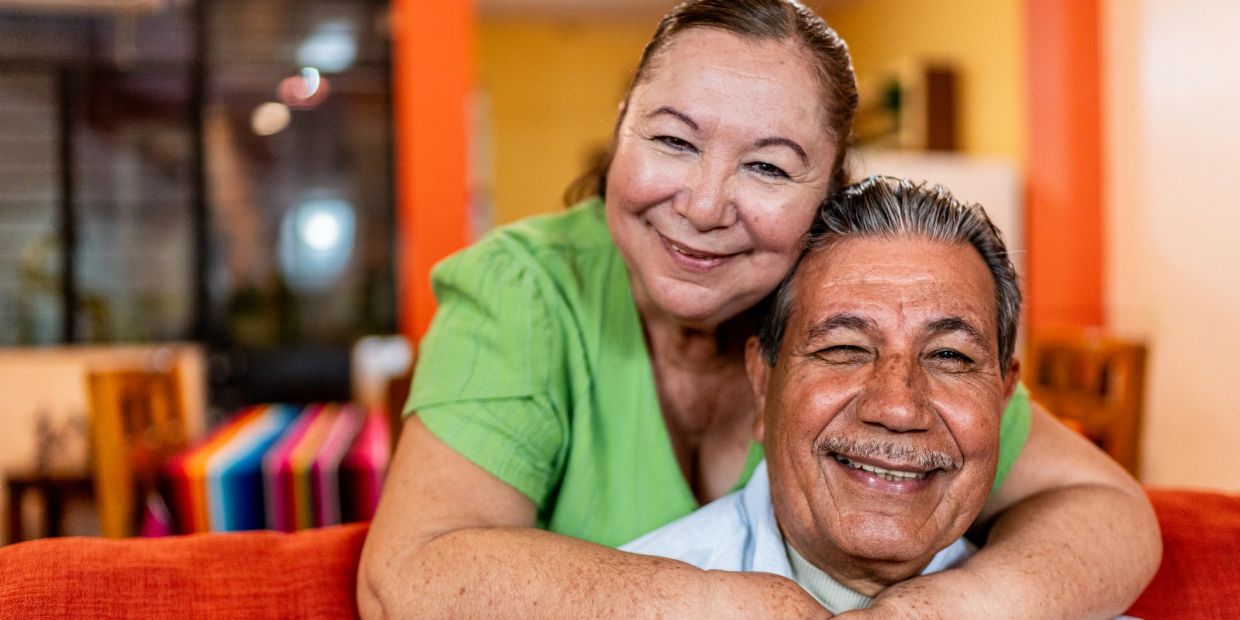 Happy elderly couple embracing and smiling warmly indoors.