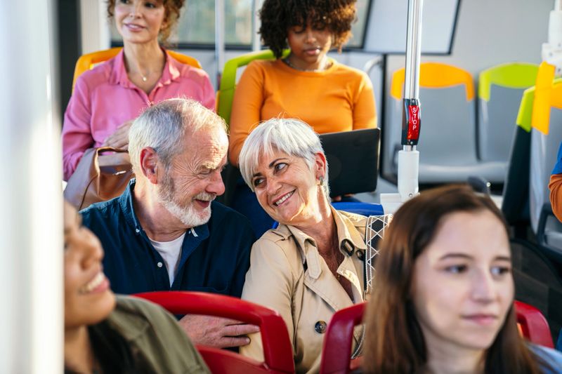 Diverse group of passengers commuting on a public bus, a senior couple laughing and interacting happily while traveling