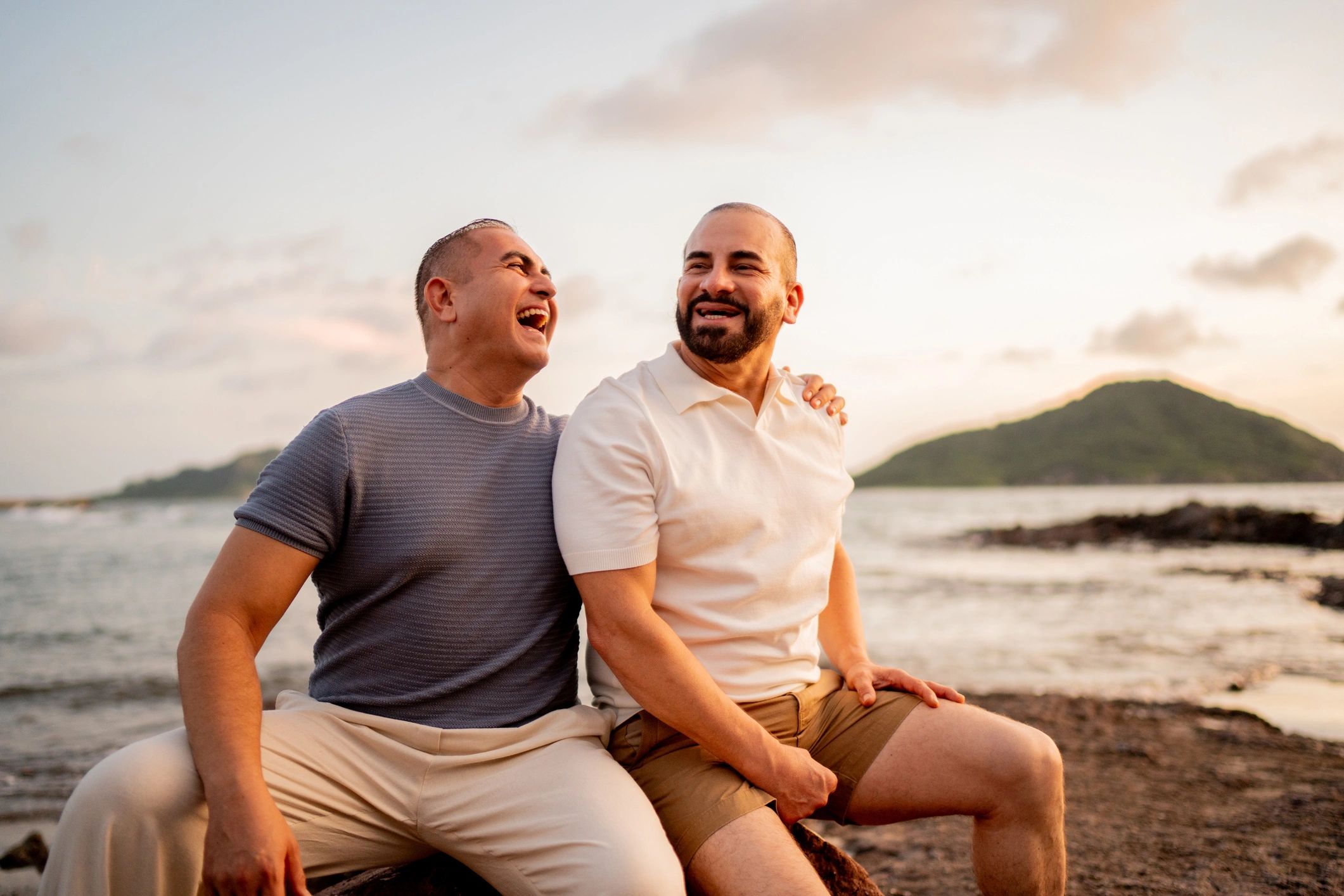 Two men enjoying a happy moment by the beach during sunset.
