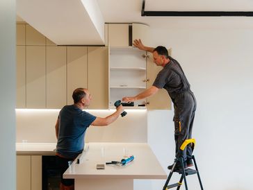 Two men installing kitchen cabinets