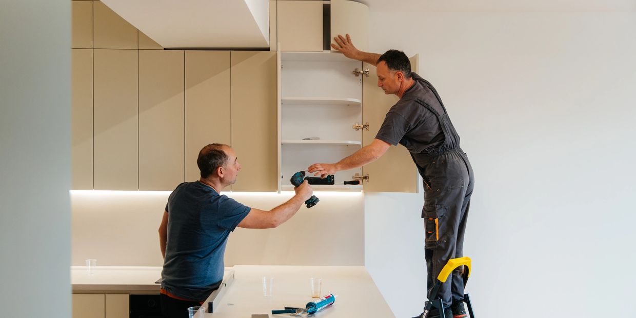 Two builders fitting a new kitchen