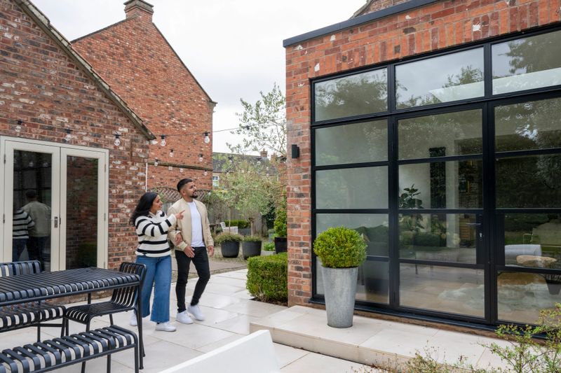 Couple in back garden looking at house, property development, home ownership, new house