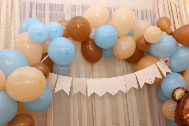 Festive beige, blue and brown balloons form an arch for decoration of a special celebration.
