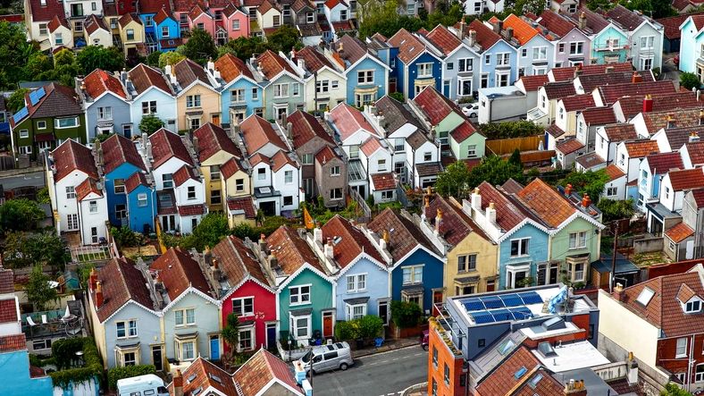 This image highlights the distinctive residential architecture of Bristol, England, featuring rows of terraced Victorian and Edwardian houses with characteristic red tiled rooftops. Some areas include pastel-colored facades, adding vibrancy to the urban landscape. The aerial perspective captures the density and uniformity of the housing pattern, reflecting the city’s historical growth during the industrial era. These neighborhoods are closely associated with community living and represent an important part of Britain’s architectural heritage, showcasing both practicality and charm. The repetitive alignment of houses demonstrates urban planning typical of 19th and early 20th century Britain, with narrow streets and green gardens interspersed between homes.