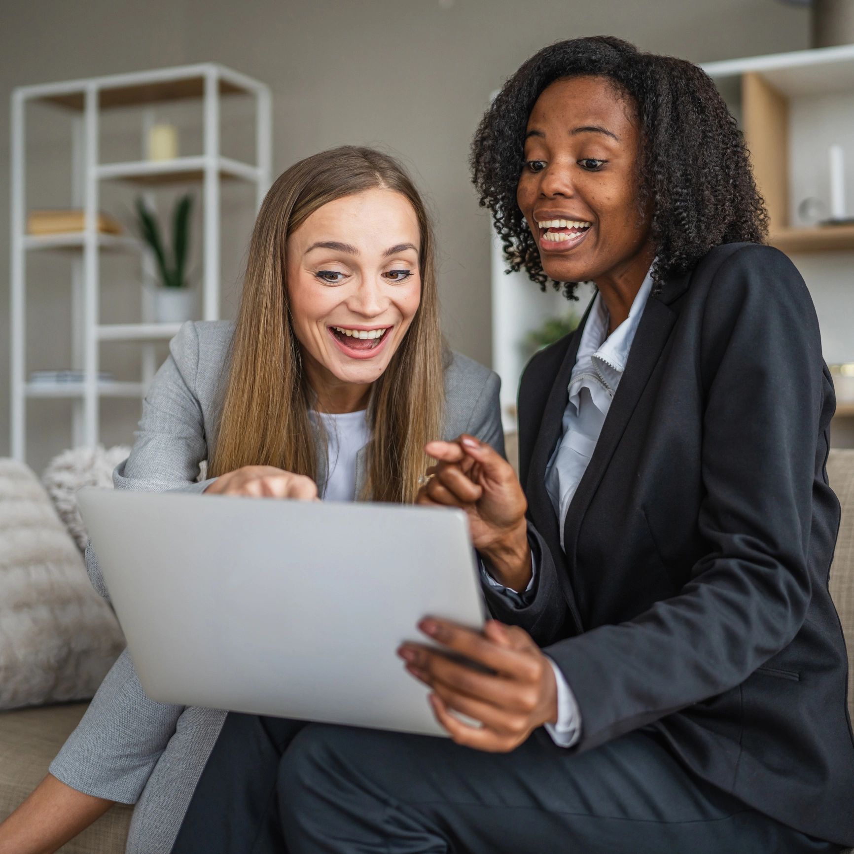 Two excited women looking at a laptop.