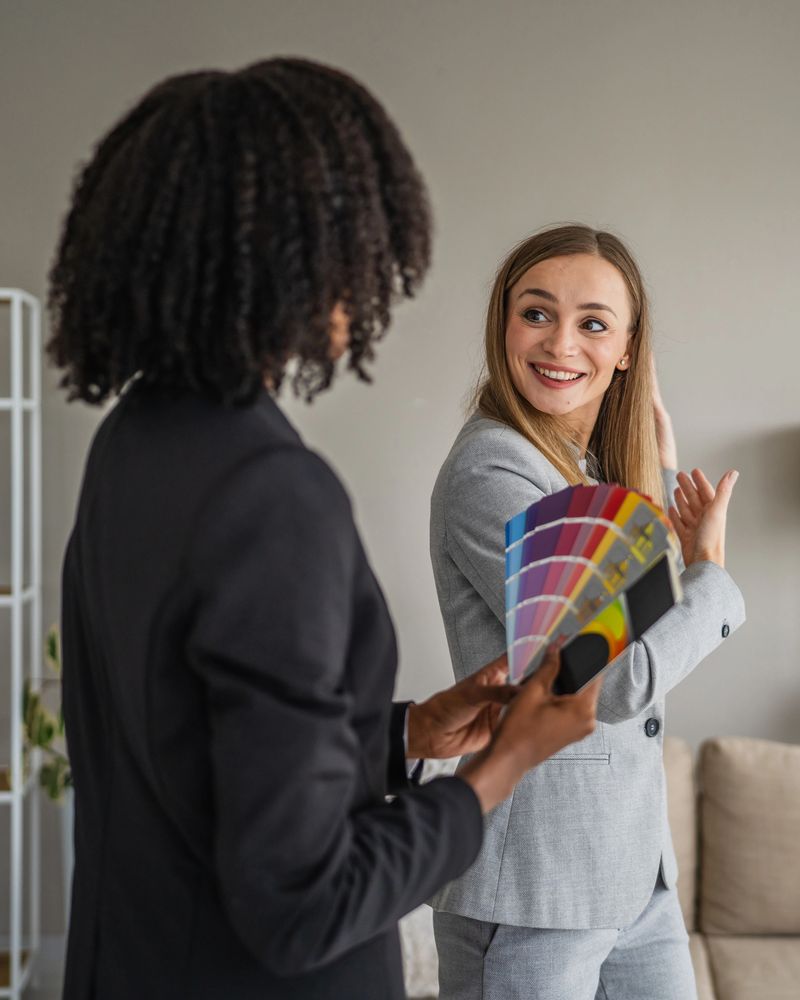 Interior designer and cheerful client reviewing paint swatches and discussing color options during a home renovation consultation, collaboration and expert guidance evident