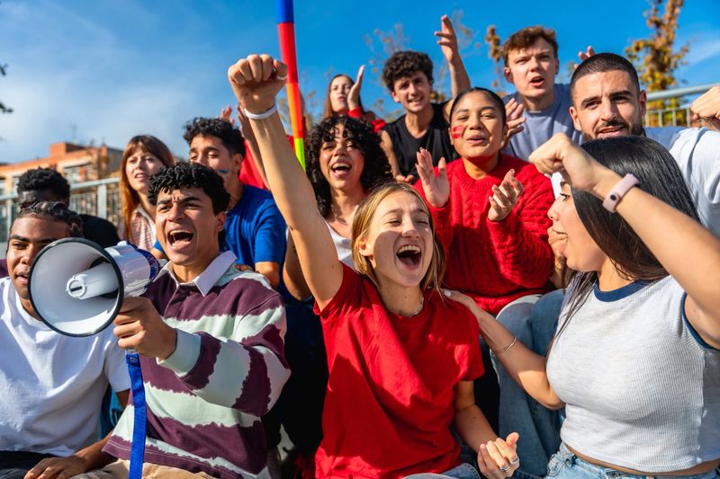 Group of diverse young adults protesting and cheering with megaphones and banners, united in energetic demonstration for social justice, empowerment and community solidarity
