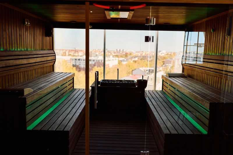 Contemporary wooden sauna providing a luxurious wellness experience with wide panoramic windows overlooking a city skyline, emphasizing relaxation and health in an exclusive spa setting