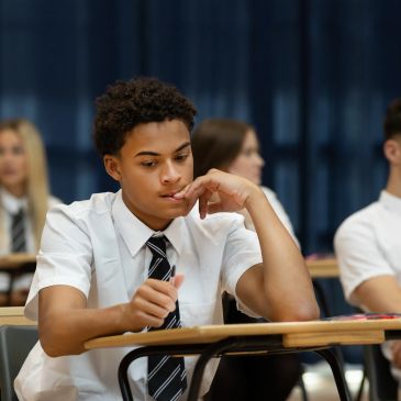 Student in uniform deep in thought during a classroom exam.