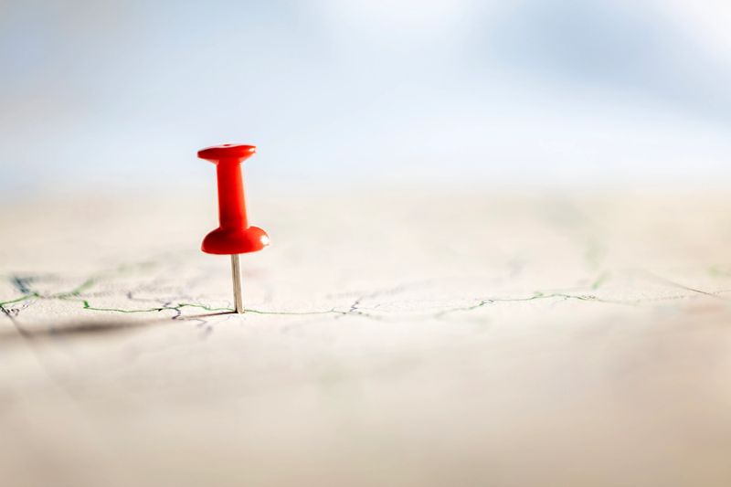 Pushpin marking the location of a destination point on a roadmap map background with copy space