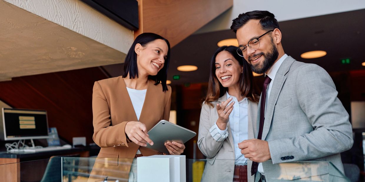 Three business professionals smiling and discussing with a tablet.