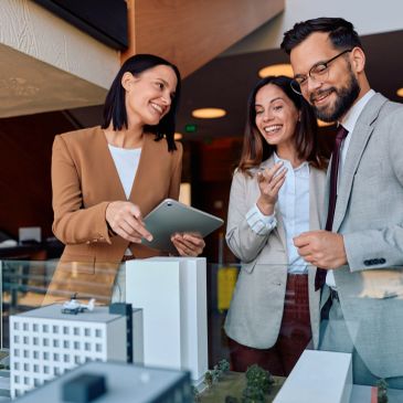 Three professionals discussing a building model.