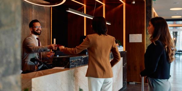 Businessman checking in a woman at hotel reception.