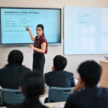 Teacher explaining Python variables and data types to students in a classroom.