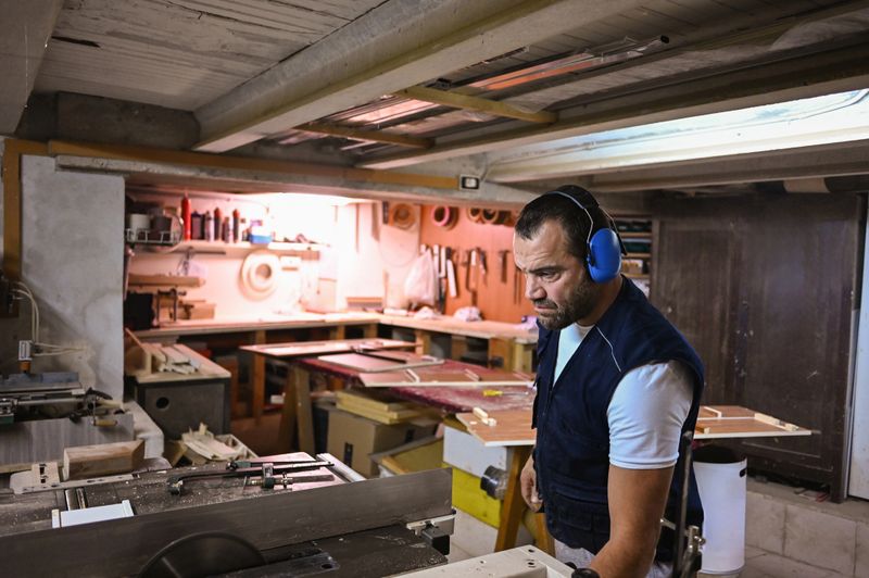 Skilled carpenter man wearing earmuffs focusing on his woodworking in a busy workshop