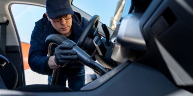 Man vacuuming the interior of a car.