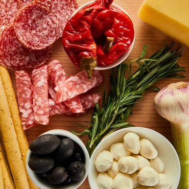 Charcuterie board with salami, cheese, olives, and herbs.