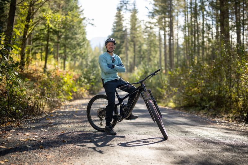 Portrait of male mountain biker pausing on rural road, backlit, Whistler, B.C.