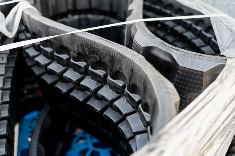 Stacked rubber excavator tracks prepared for transport, illustrating heavy machinery components, industrial equipment logistics, construction parts packaging and durable material supply in engineering industry