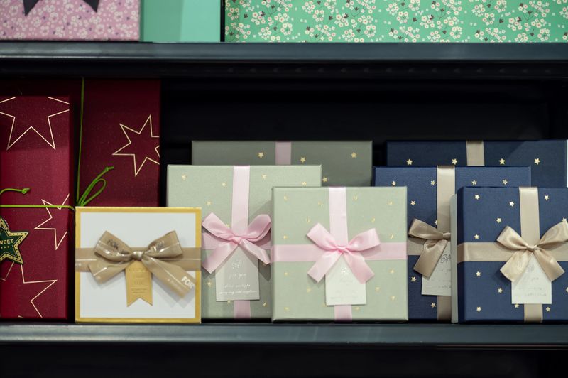 Beautifully wrapped gift boxes with bows in different colors and textures arranged on store shelf. Festive packaging concept for celebration, holiday shopping, or special occasions.
